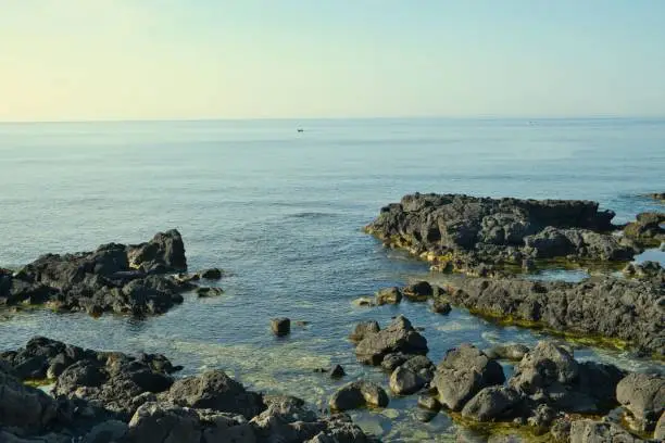 Photo of View over the volcanic rocks to the blue sea in Giardini Naxos, Sicily