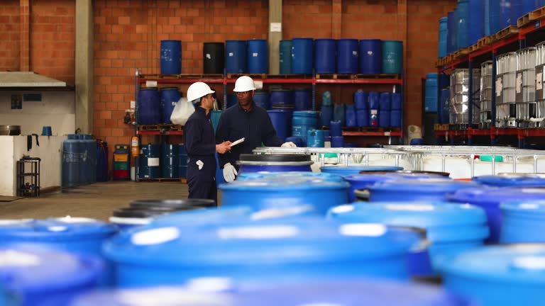 Foreman talking to an African American worker at a chemical plant while doing an inventory