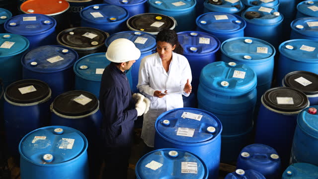 Female supervisor talking with an employee about a batch of chemical drums they produced at the factory