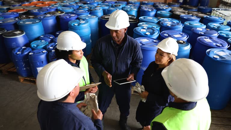 Black male leader assigning tasks to his team before starting their shift at a chemical plant