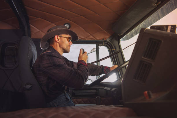 Cowboy Truck Driver Caucasian Trucker Wearing Western Style Outfit Driving His Semi Truck and Talking Through CB Radio. Side View. semi truck audio stock pictures, royalty-free photos & images