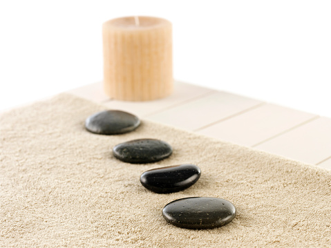 Still life of black volcanic rocks on a towel with candle on wooden table