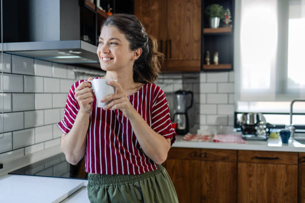 istock Woman smiling as she enjoys her coffee in the kitchen 1561377362