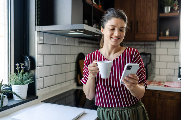 istock Morning connectivity: woman's contented coffee break with phone 1561377374