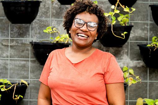 Portrait of mature african woman cheerfully smiling while standing in front of a green wall