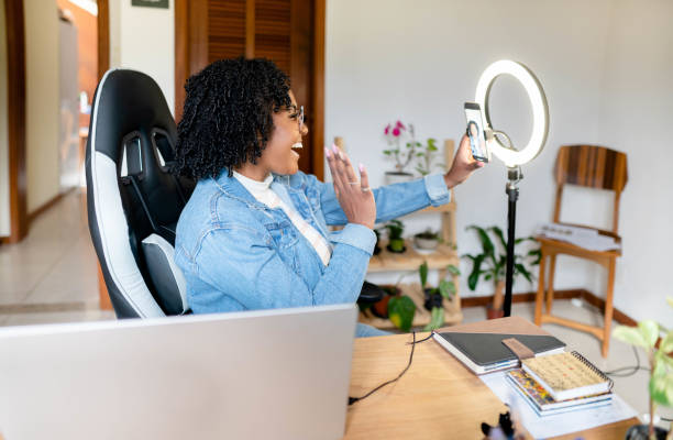 istock Young woman waving during a live streaming vlog from home 1561426378