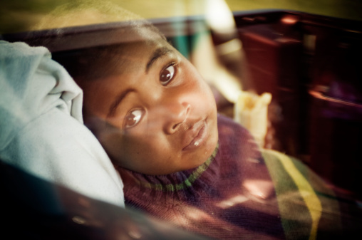 Portrait of young sick boy in lying in a car.