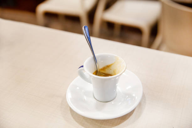 |Cup of Espresso  - quick  prepared  Italian coffee on table with spoon. It is relatively cheap with small quaintity of water in railroad station or airport