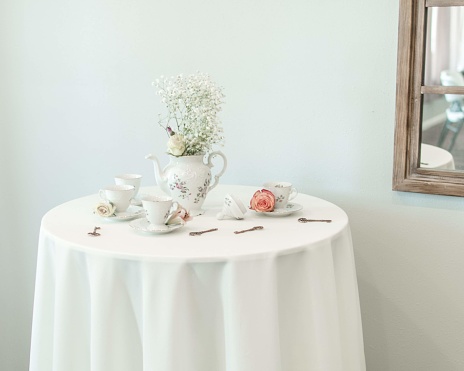 table scape with white tablecloth and tea set teapot case with bouquet of flowers