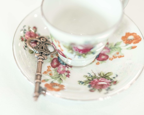 floral tea set with skeleton key atop a white tablecloth