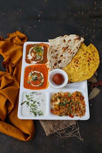 Indian food thali with dal makhani, paneer, raita, biryani, gulab jamun and naan