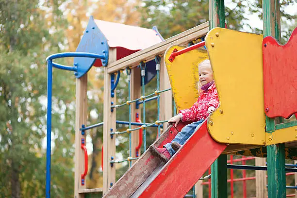 Photo of Adorable little girl preparing to slither from a slide