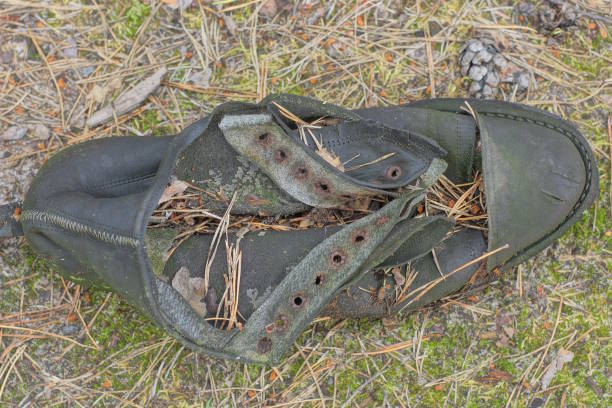 istock one old black dirty torn leather shoe lies on the ground 1561496094