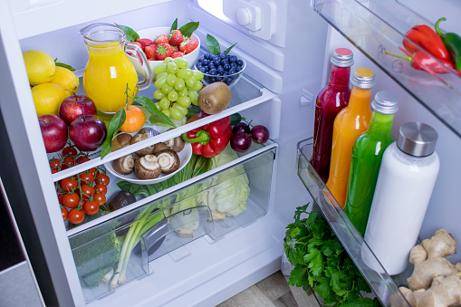 Food photography of a clean fridge filled with healthy vegan foods such as fruits vegetables, juices and plant milk