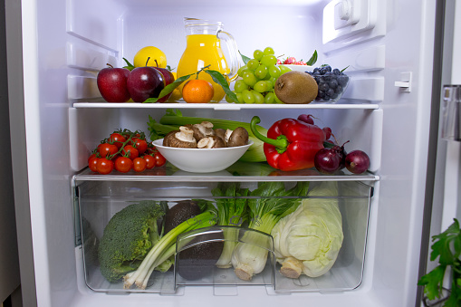 Food photography of a clean fridge filled with healthy vegan foods such as fruits vegetables, juices and plant milk