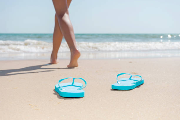 ビーチの女性の足がビーチサンダルから海に向かって歩いています。 - shoe leaving women summer ストックフォトと画像