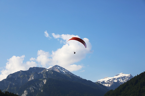 Paragliding from a peak over the mountains on an overcast day,in a highly forested area.