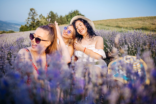 Young women having fun sitting in the flower field in nature
