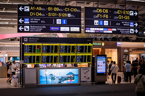 Passengers walk past digital sign boards displaying departure times inside of the  international departures terminal at Suvarnabhumi Airport in Bangkok. International travel at Suvarnabhumi Airport (BKK) in Bangkok, Thiland on July 22, 2023.