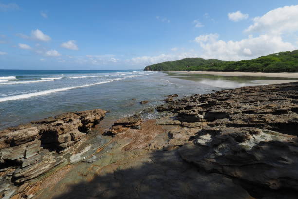 El Coco Beach, Nicaragua. Playa El Coco, Nicaragua, on a sunny summer day showing its beach, rocks, vegetation and cloudscape. el coco stock pictures, royalty-free photos & images