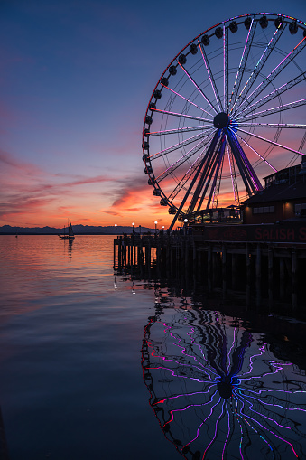 Seattle, USA - Jun 27, 2023: Sunset over Elliott Bay on the waterfront with a Sailboat and the Seattle Great Wheel.