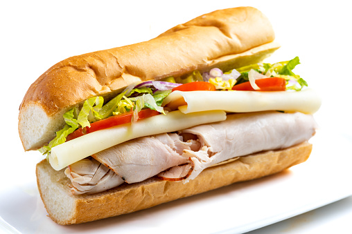 Sliced Turkey meat, Cheese, lettuce and tomato submarine sandwich on white background