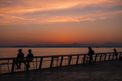 Seattle, USA - Sep 21, 2022: A vivid sunset on Elliott bay off pier 62 as people enjoy the warm weather.