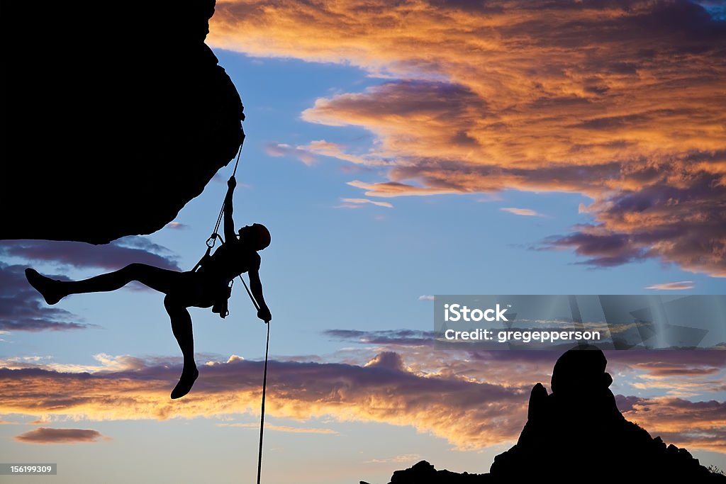 Climber rappelling. A climber dangles in midair as she rappels from the summit of a rock spire after a successful ascent in The Sierra Nevada Mountains, California. Balance Stock Photo