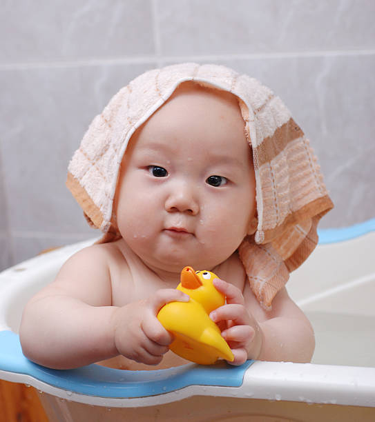 istock Baby getting a bath plays with a toy rubber duck 156199361