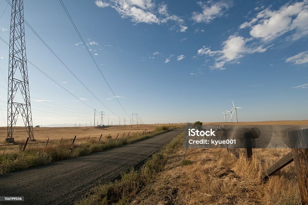 Road to Alternative Energy Wind turbines on the right. Power lines on the left. Road goes from left to right, between the wind turbines and the power lines. Cable Stock Photo