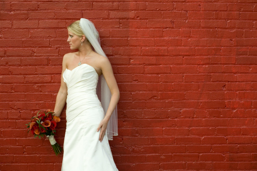 Horizontal photo of bride standing in front of red brick background