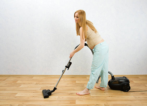 Pregnant woman cleaning floor with vacuum cleaner stock photo