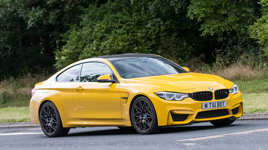 Milton Keynes,UK - July 21st 2023: 2018 yellow BMW M4 car driving on an English road