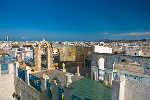 Tunisia. Tunis - old town (medina). Terrace of Palais d'Orient with ornamental arches and wall covered tiles. There is skyline of east-south town in background