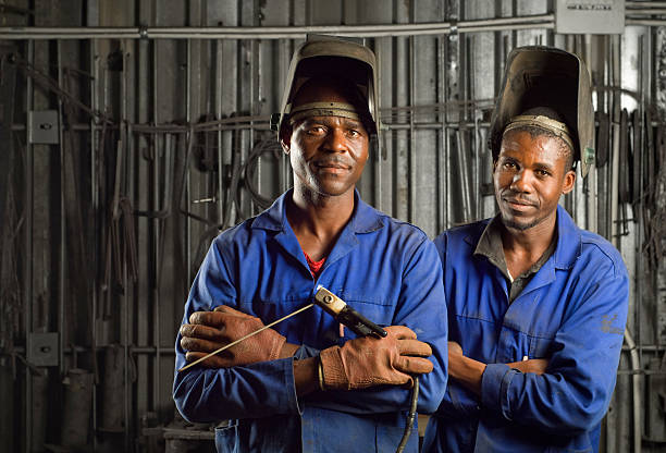afrikanischer schweißer mit maske - welder manual worker african descent steel worker stock-fotos und bilder