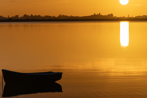 Silhouette of a man fishing in a canoe on a still morning.