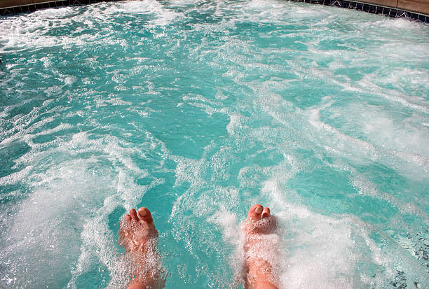 Feet soaking in warm blue-green waters of a hot tub hot tub