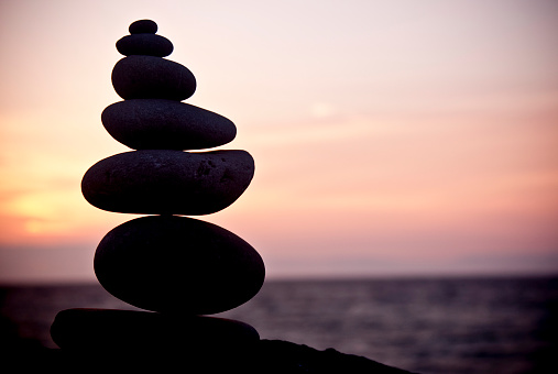 A stack of rocks on a beach log, with the Straights of Juan de Fuca in the distance. 