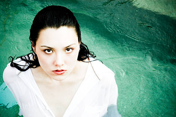 Woman wearing a white shirt, standing in water.