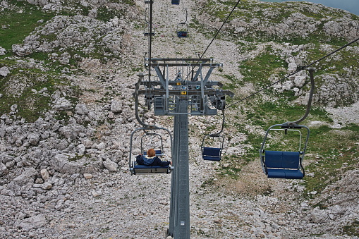 Senior woman sitting on cable car while riding over scenic landscape of Italian Dolomites
