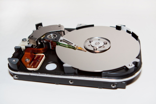 An exposed hard disk drive platter and head.