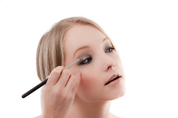 Young woman applies makeup with a soft brush beautiful skin stock photo