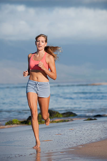 Fit Young Woman Jogs on Beach stock photo