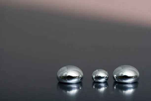 Shiny Mercury drops on a grey background