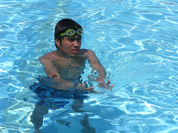 A boy with glasses in the pool.