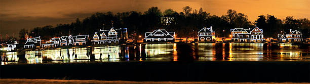 View of brightly lit gazebo with people having evening party in Midwestern park by lake; gazebo and trees around it reflect in water; dark sky in background