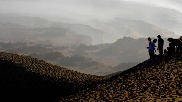 istock Friends on Sahara Dunes with Atlantic Ocean Cliffs in Background in Morocco 1562174242