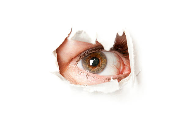 istock Eye looking through  hole in a paper 156220568