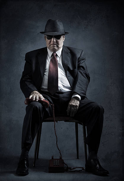 elegant senior man with vintage phone old mafia hitman having problems answering a phone call - background composite of grunge scratched papers mafia boss stock pictures, royalty-free photos & images