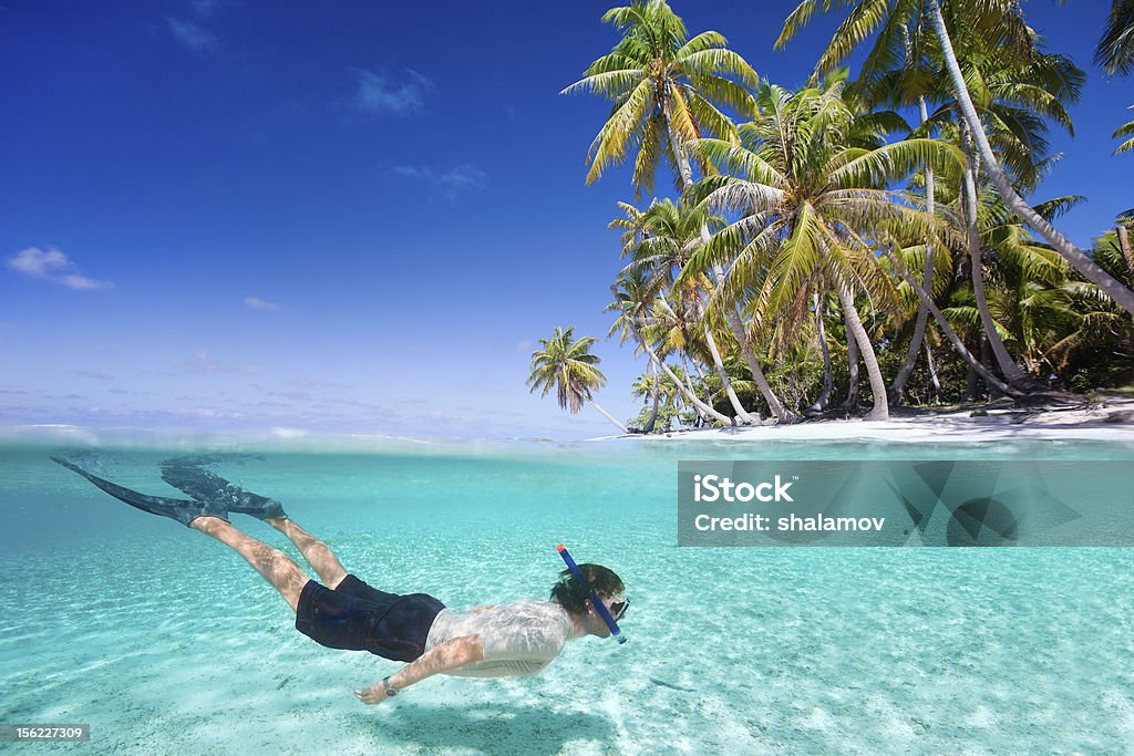 Man with snorkel swimming underwater Man swimming in a clear tropical waters in front of exotic island Snorkel Stock Photo